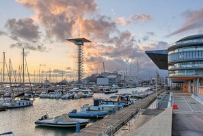 A marina with various boats docked, a tall communication tower, and a modern building with a curved facade. - Apartment 'La Casa Di Cla' with Wi-Fi and Air Conditioning (Genova)