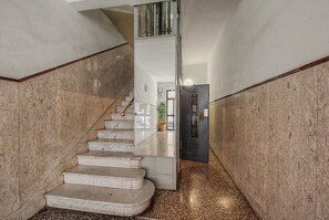 Una escala de marbre que porta a una plataforma, flanquejada per parets amb acabat texturat.