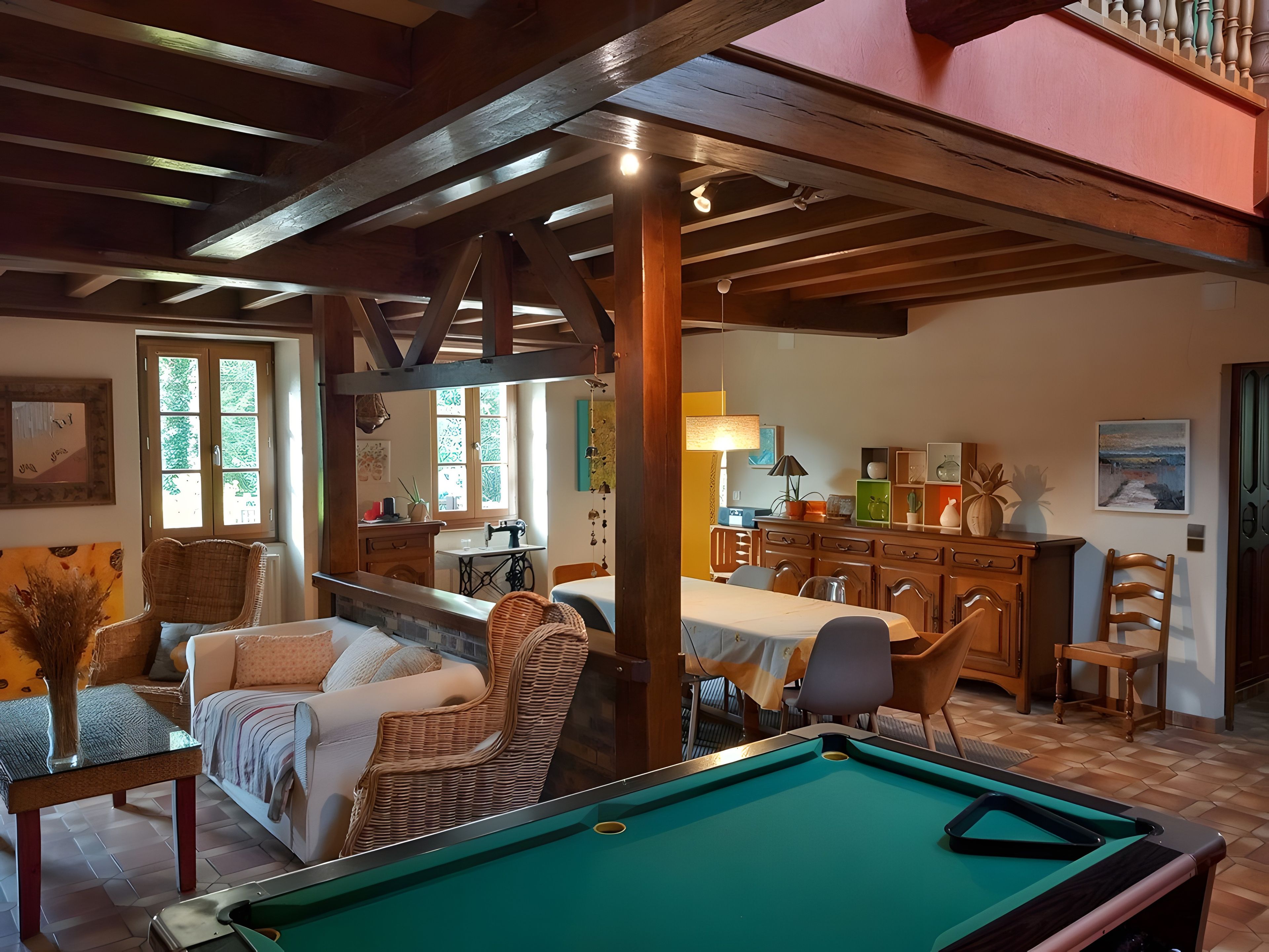 A cozy room with a pool table, comfortable seating, and a kitchen area.