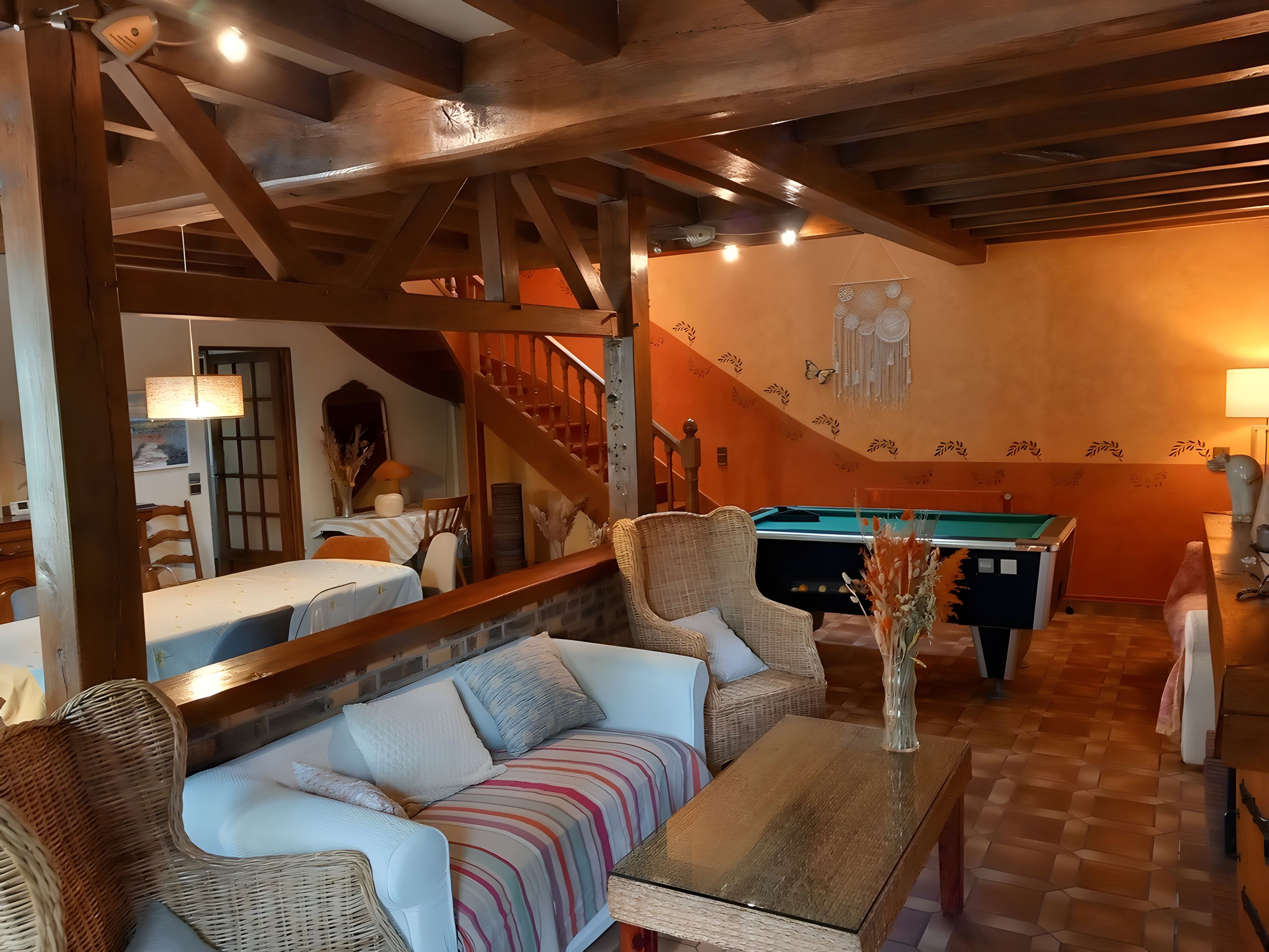 A cozy living room with a pool table, a sofa, and a dining area.