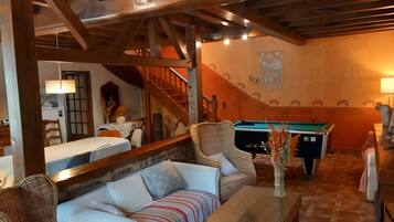 A cozy living room with a pool table, a sofa, and a dining area.