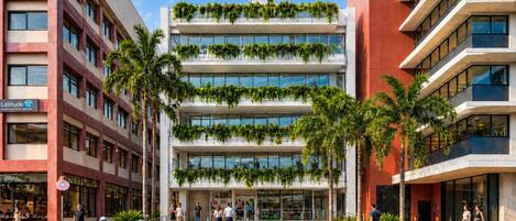 Ein mehrstöckiges Gebäude mit modernem Design, mit begrünten Balkonen und blauem Himmel.