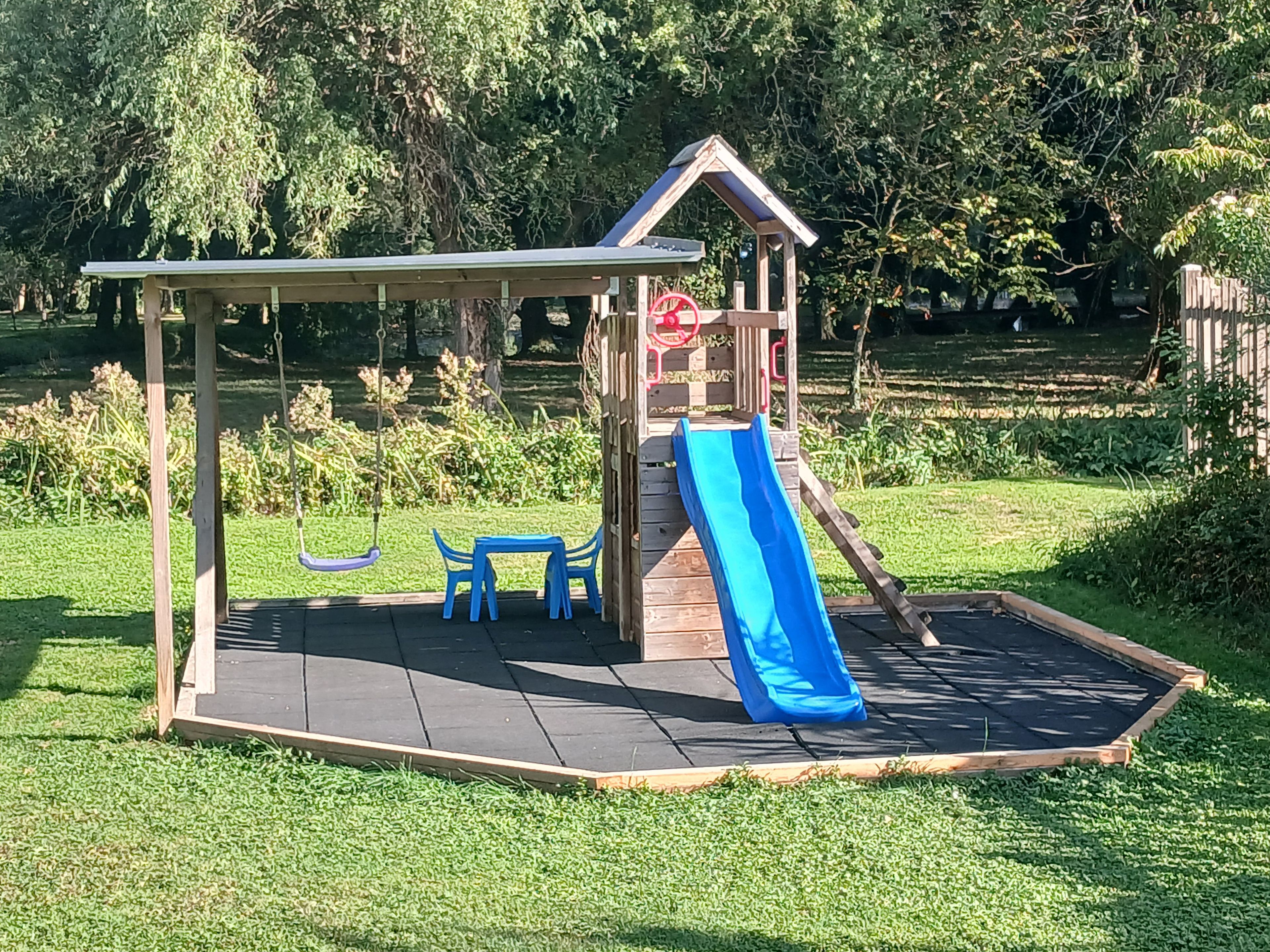 A playground with a slide, swing set, and picnic table.