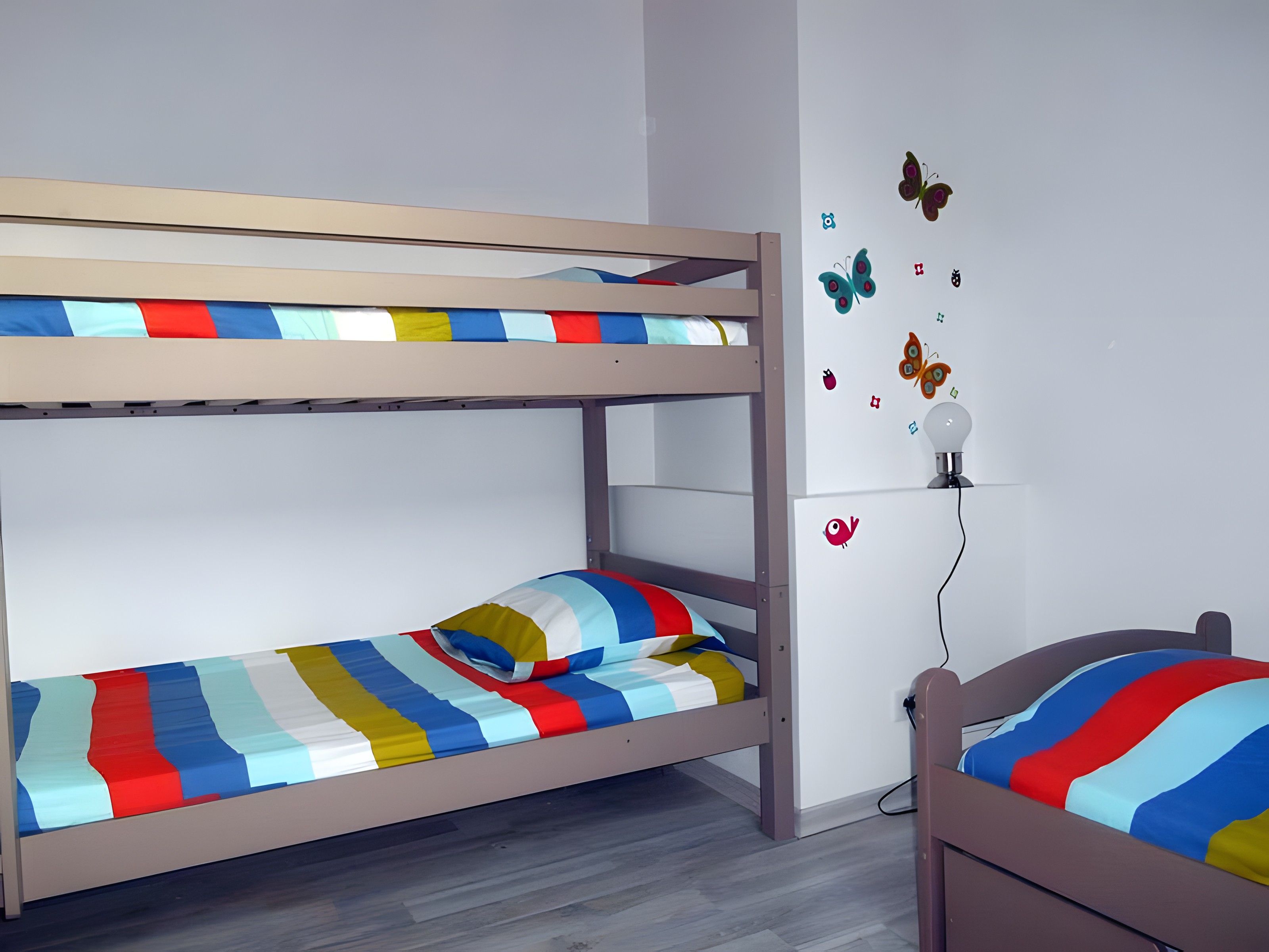 A bunk bed with striped bedding and a wall-mounted lamp.