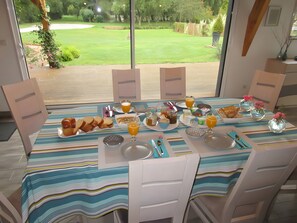 A dining table set for breakfast with a view of a golf course. - Guest Rooms 'La Maison Des Étangs  La Nature' with Lake View, Wi-Fi and Air Conditioning (Vinon)