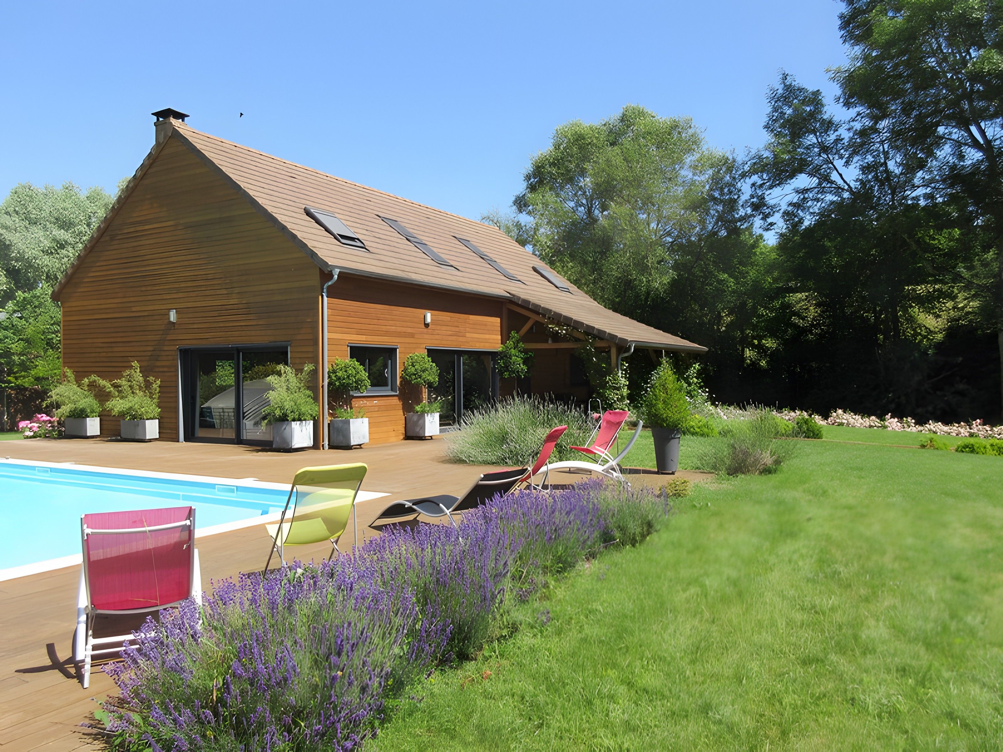 Et moderne hus med swimmingpool, udendørs møbler og en velplejet have.