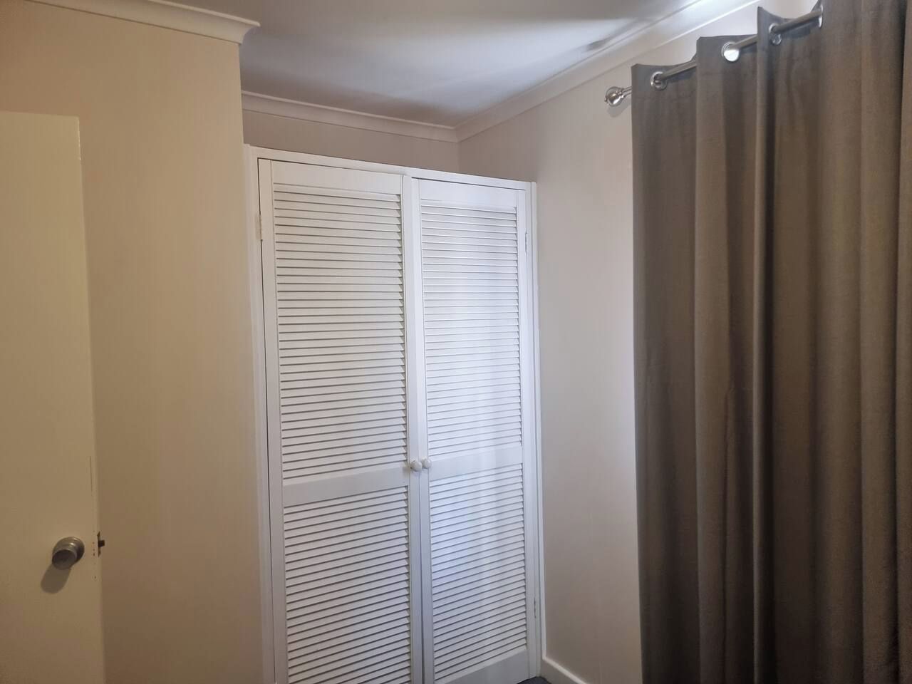 A room with a white closet, a door, and a curtain.
