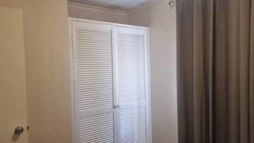 A room with a white closet, a door, and a curtain.