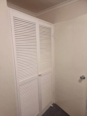 A white closet with horizontal louvered doors and a silver doorknob. - Entire 3 bedroom unit- 5 min to CBD, Hannan street (Piccadilly)