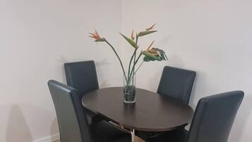 A dining area with a round table, four chairs, and a vase with flowers.