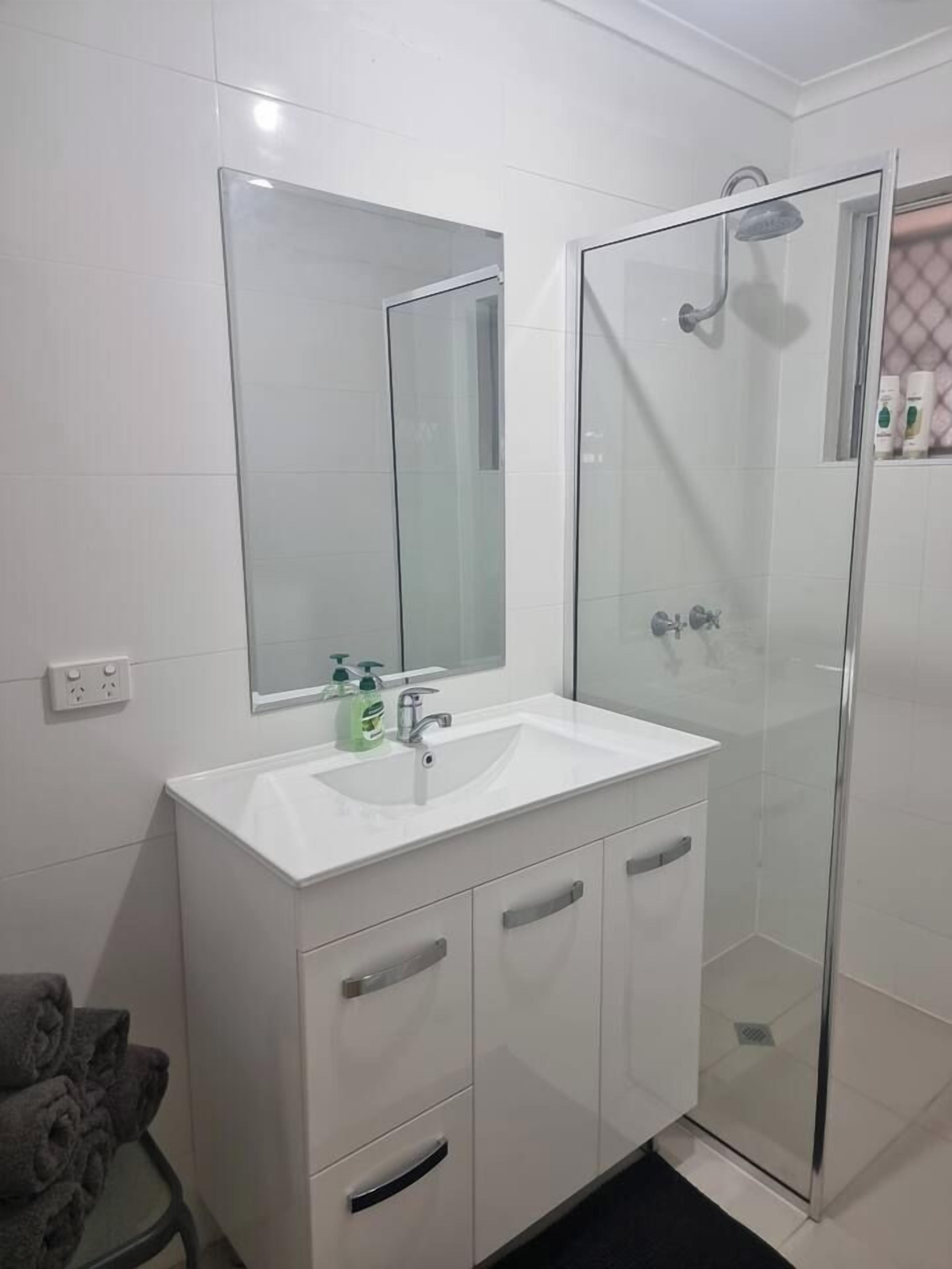 A bathroom with a white sink, mirror, and glass shower enclosure.