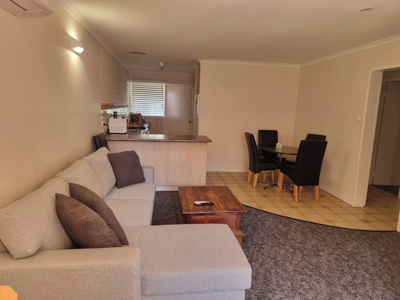 A living room with a sofa, a coffee table, and a dining area with chairs and a table.