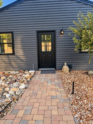 A house with a black front door, a small porch, and a gravel pathway leading to the entrance.