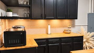 A compact kitchen with black cabinets, a microwave, and a wooden countertop.
