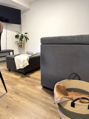 Ein modernes Wohnzimmer mit einem grauen Sofa, einem kleinen Tisch und einer Stehlampe.