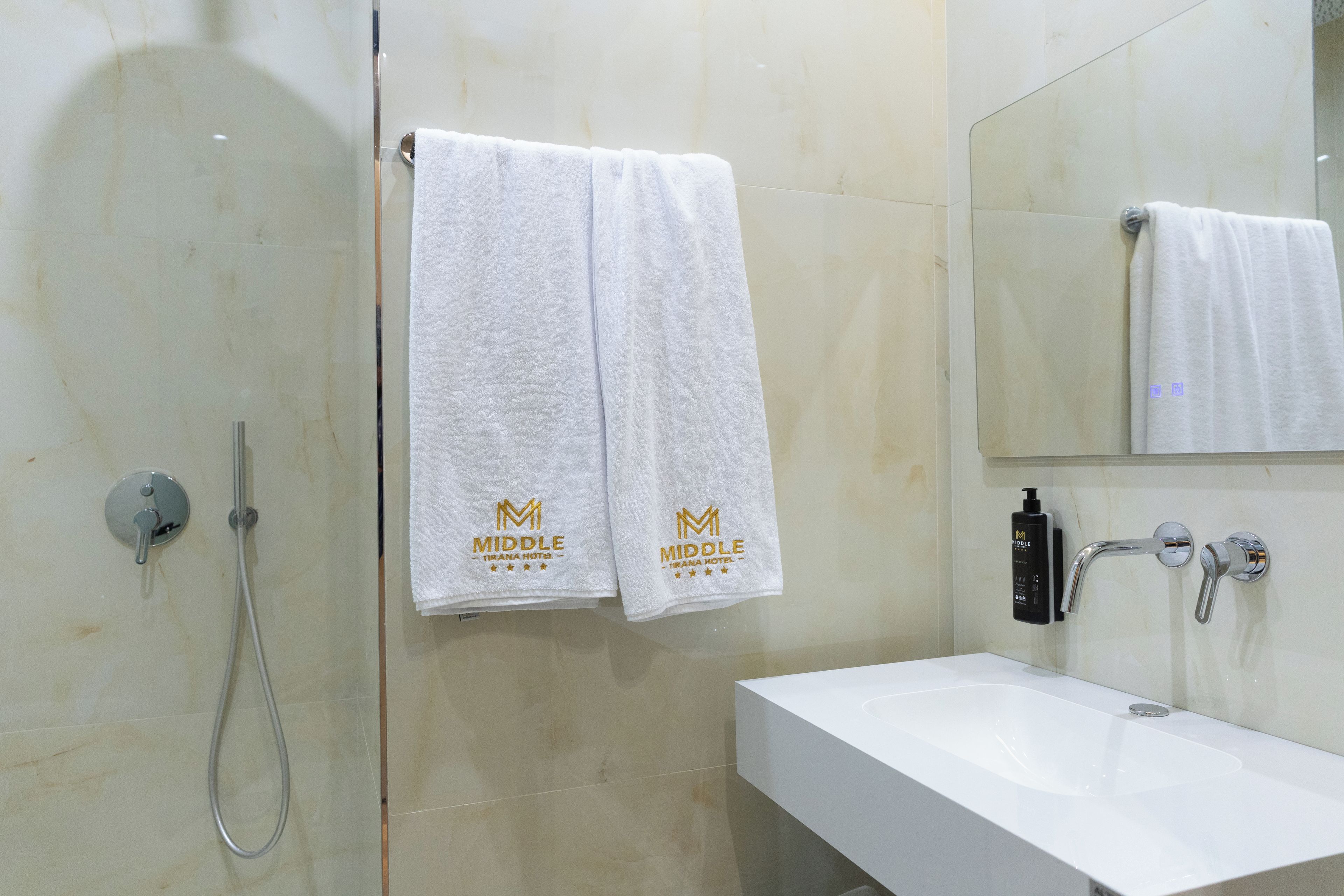 Un baño con ducha, un lavabo y dos toallas colgadas en la pared.
