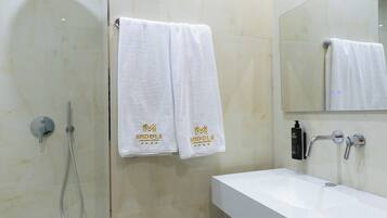Un baño con ducha, un lavabo y dos toallas colgadas en la pared.