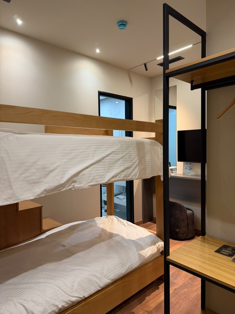 Habitación con literas, un escritorio, una silla, un espejo y una ventana.