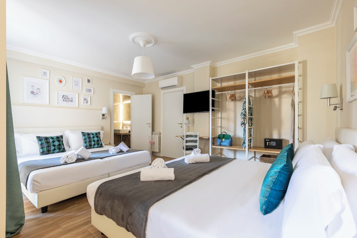 Ein Hotelzimmer mit zwei Betten, einem Fernseher, einem Kleiderschrank und einem Badezimmer.