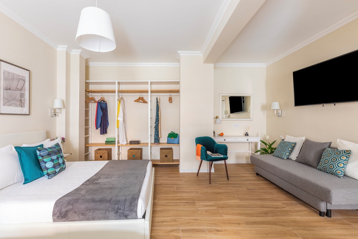 Ein modernes Schlafzimmer mit Bett, Sofa, Schreibtisch und Kleiderschrank.