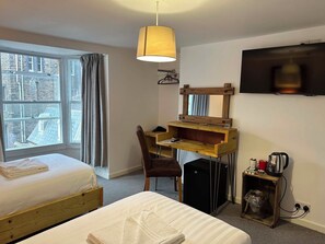 A hotel room with a bed, a desk, a chair, a TV, and a window with curtains. - The Pier Hotel (Aberystwyth)