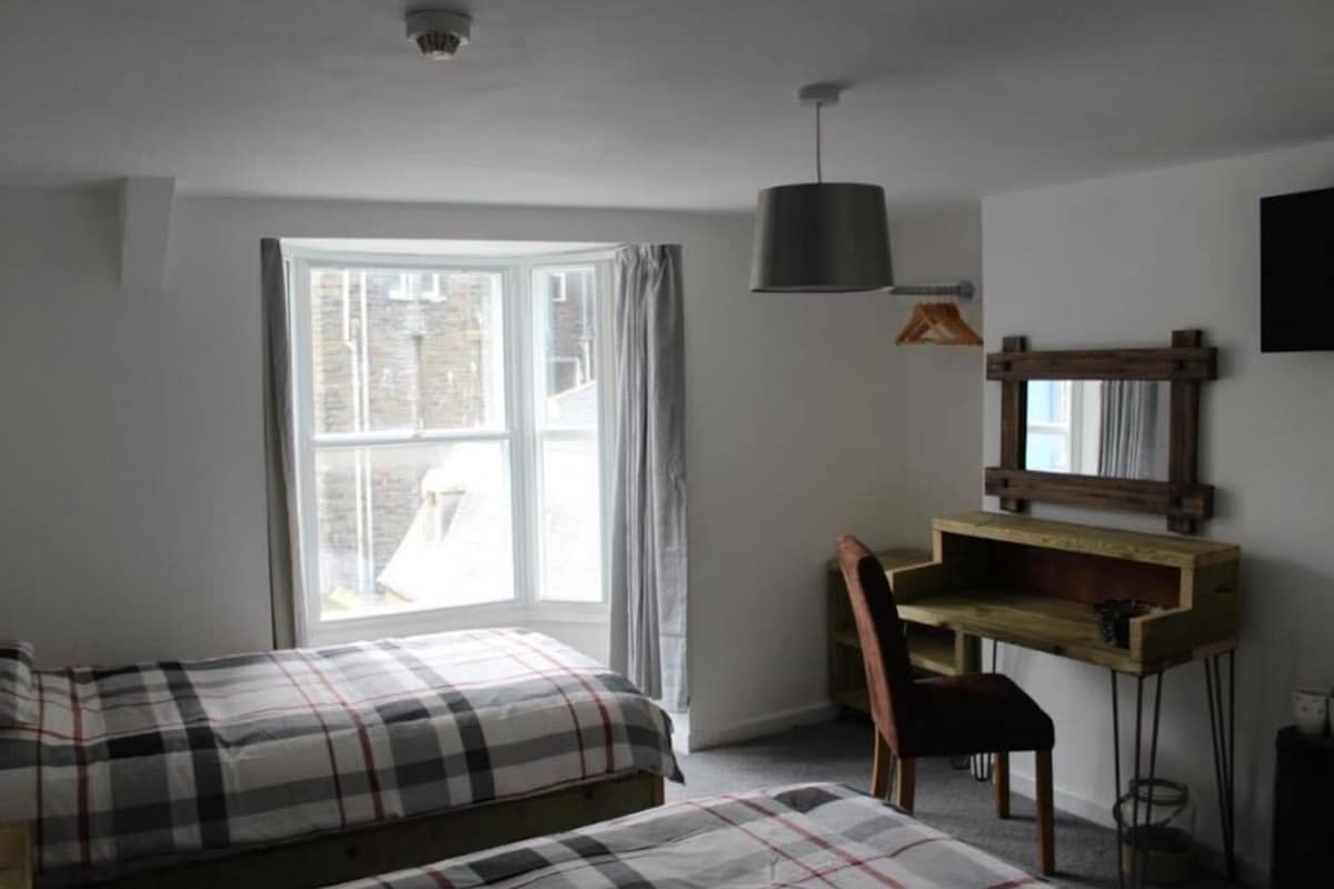 A bedroom with a bed, a desk, and a chair.