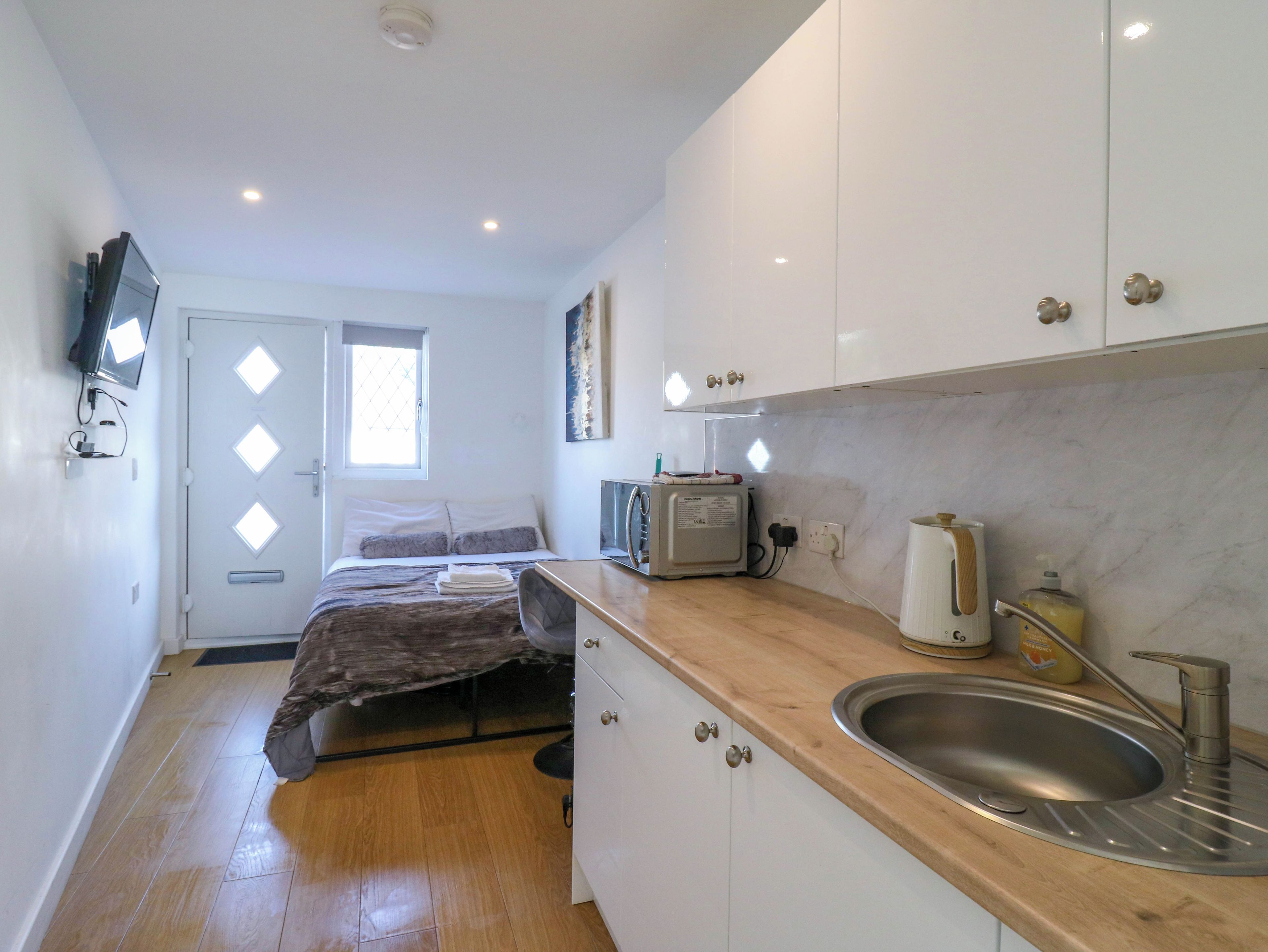A compact kitchen with a sink, a toaster, and a window.
