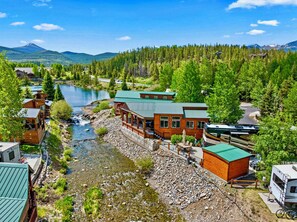 A lodge with a river view, wooden cabins, and a mountain backdrop. - Newly Listed Breckenridge Riverfront Retreat with Mountain View’s (Breckenridge)