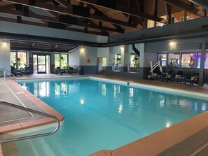 Une piscine intérieure à l’eau claire, entourée de chaises longues et d’un espace salon abrité.