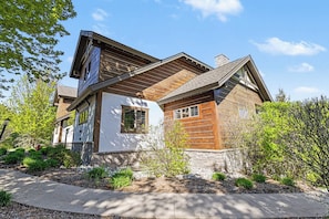 A two-story house with a stone foundation, wooden siding, and a sloped roof. - Boyne Mountain Ski/In-Out Condo W/Hot tub Sleeps 12 (Boyne Falls)