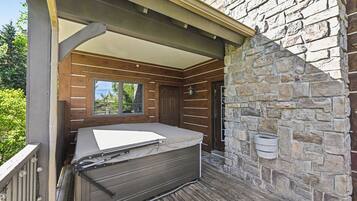 A covered outdoor seating area with a stone wall and a wooden deck.