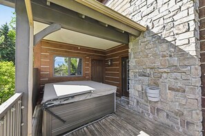 A covered outdoor seating area with a stone wall and a wooden deck. - Boyne Mountain Ski/In-Out Condo W/Hot tub Sleeps 12 (Boyne Falls)