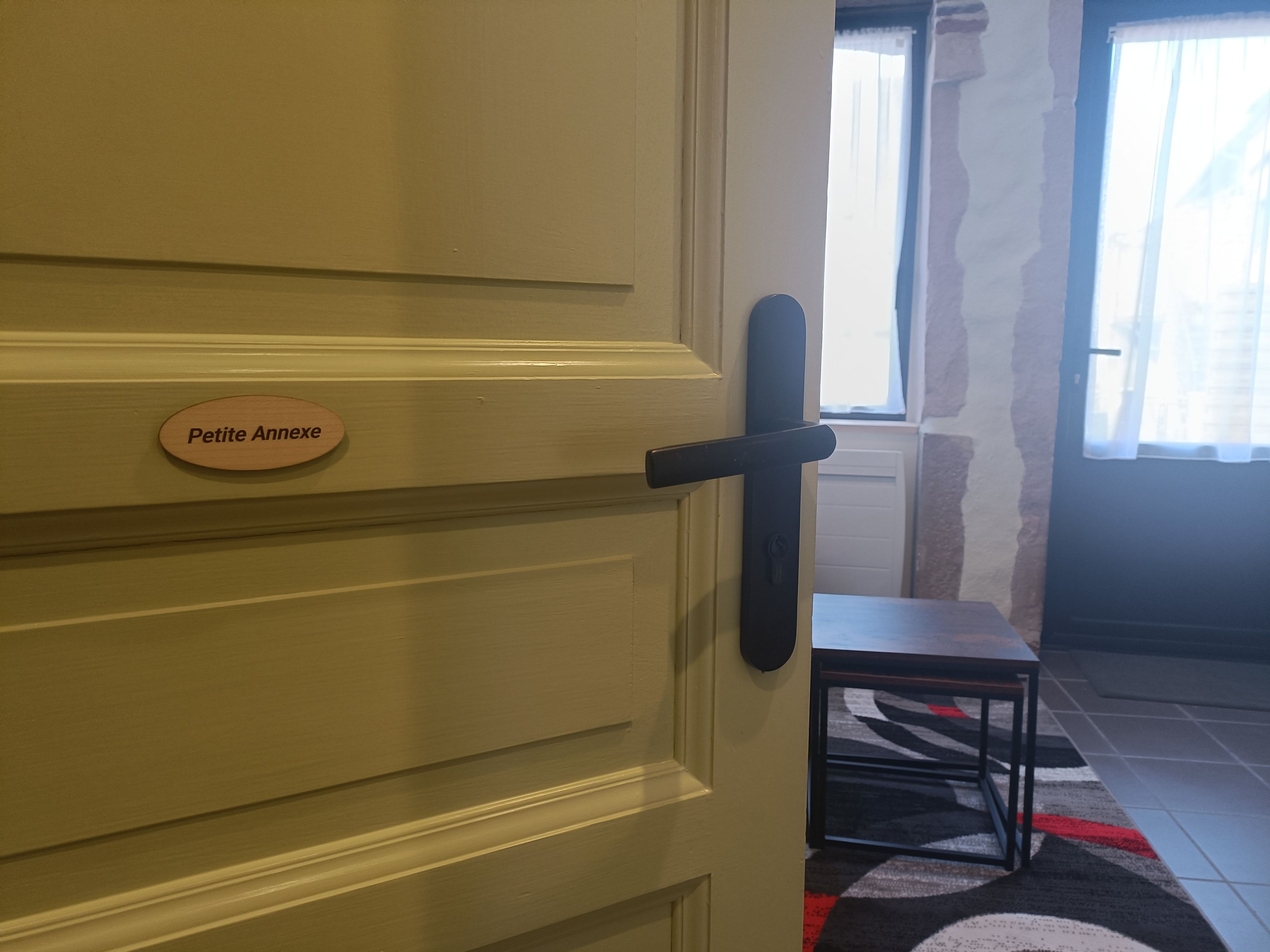 Una porta con una targa che riporta la scritta 'Petite Annexe' e un maniglia nera.