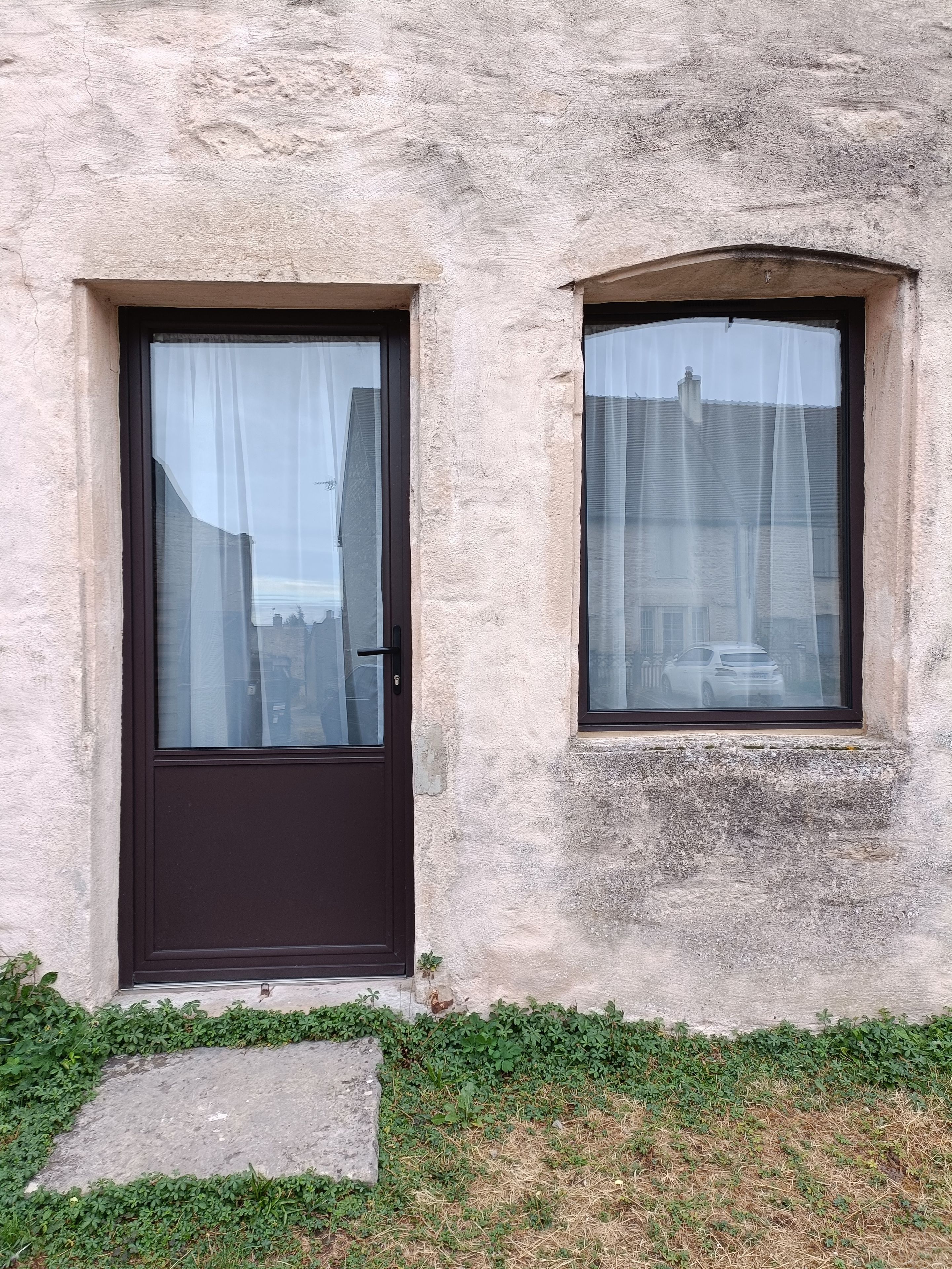 Un edificio con una porta e una finestra, entrambi con tende.