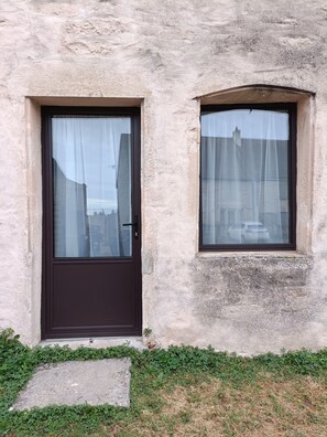 A building with a single door and a window, both with curtains.