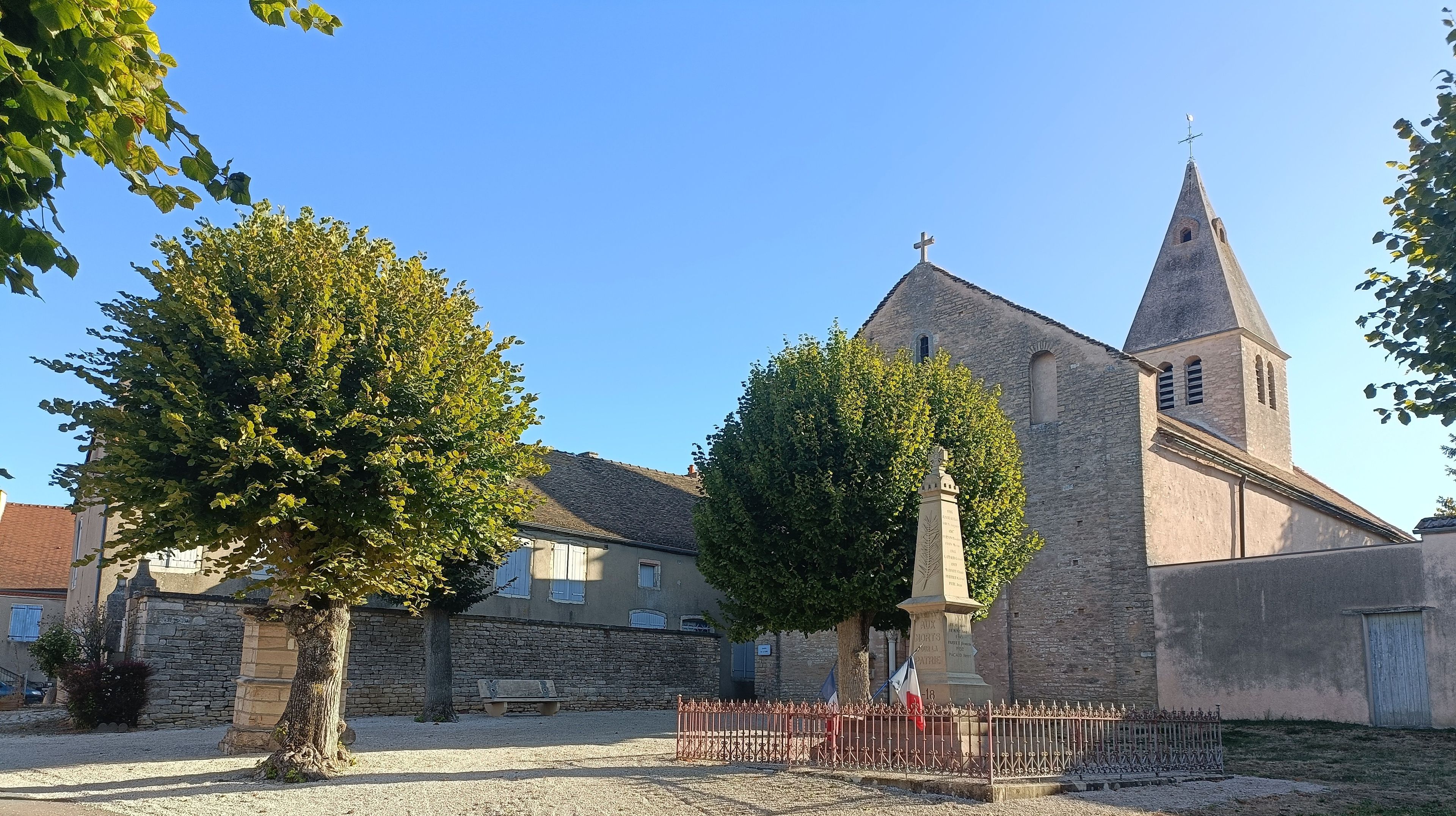 Une église dotée d’un clocher imposant et d’un bâtiment en pierre, avec un drapeau devant.