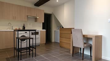 Een moderne keuken met houten kastjes, een inbouwoven en een wasmachine.