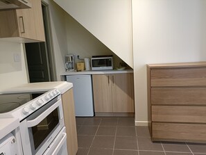 Una cucina compatta con forno integrato, microonde e macchina del caffè sul piano di lavoro.