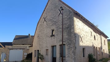 Een landelijk gebouw met een flauw hellend dak, een grote deur en een klein raam.