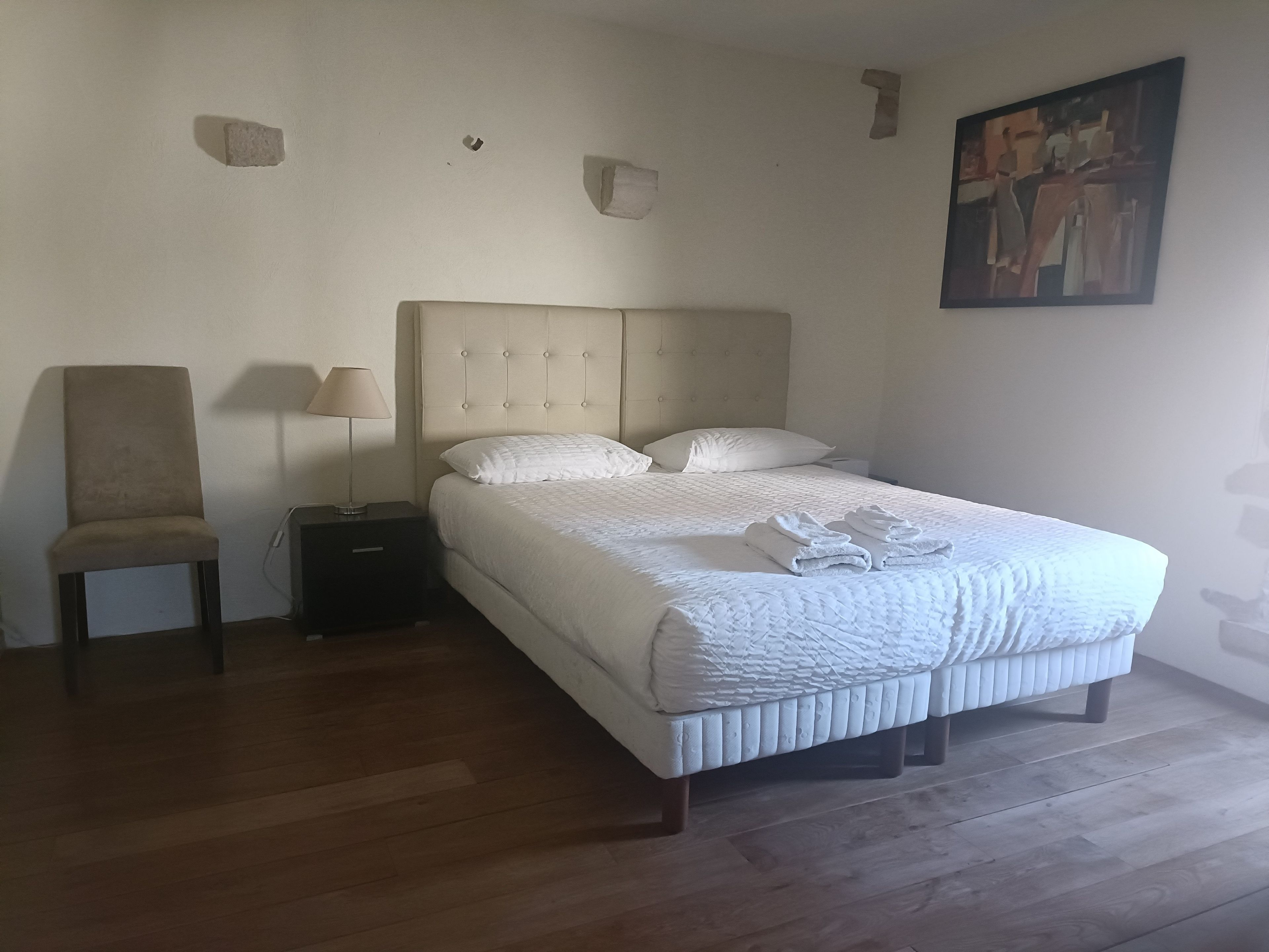 Una camera da letto con un letto, una sedia, un comodino e una lampada.