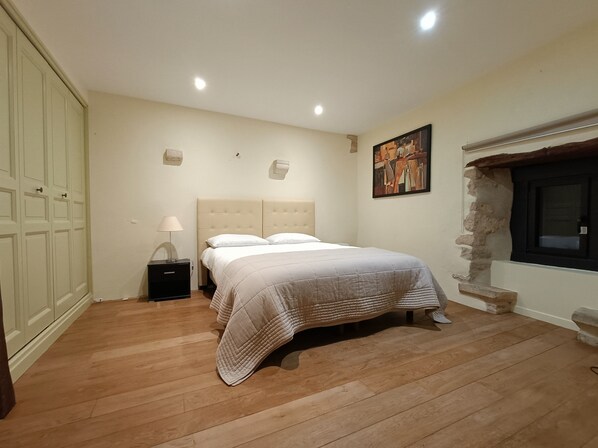 A bedroom with a bed, nightstand, and a stone wall.