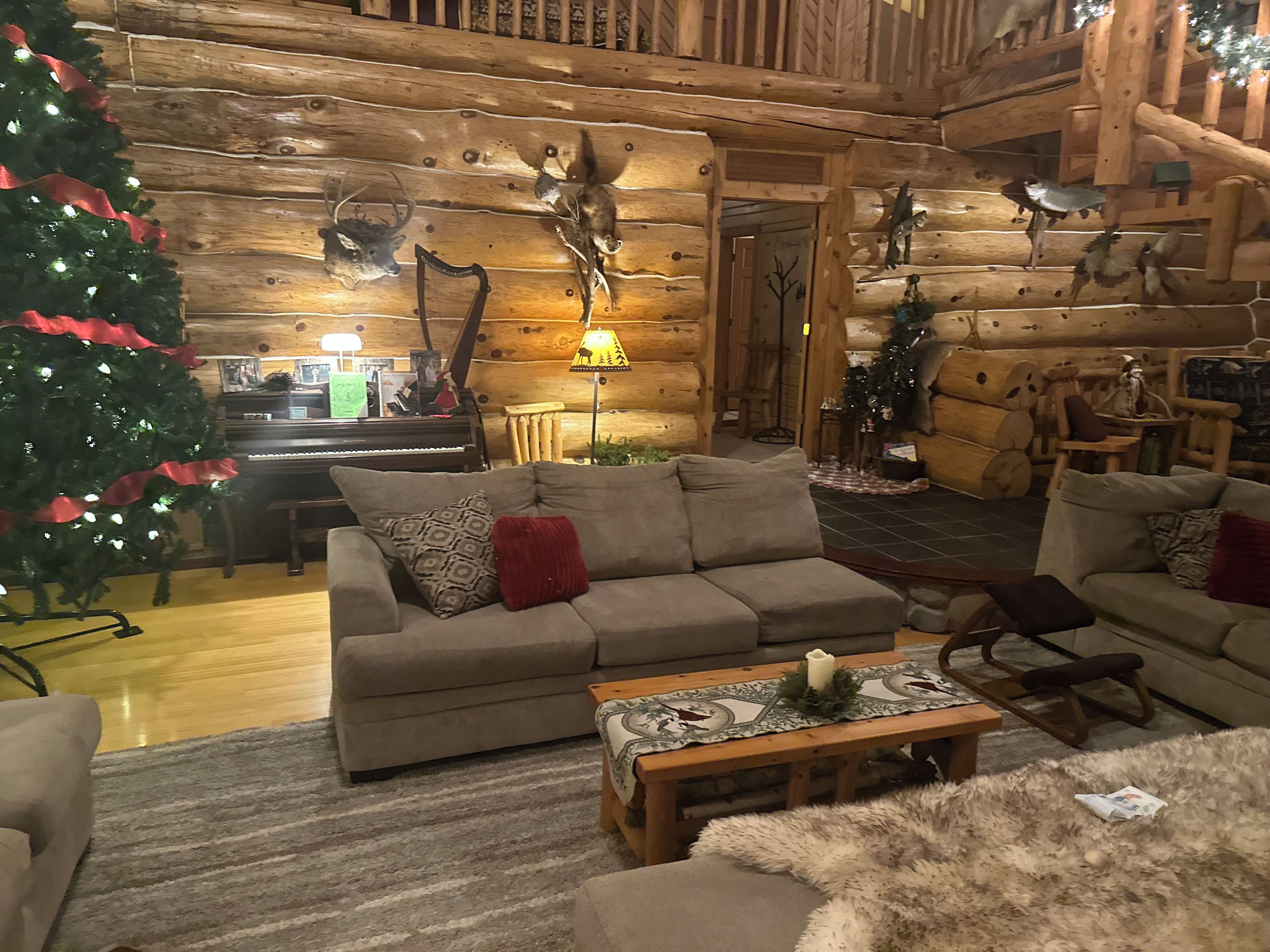 A cozy log cabin interior with a sofa, a Christmas tree, and rustic decor.
