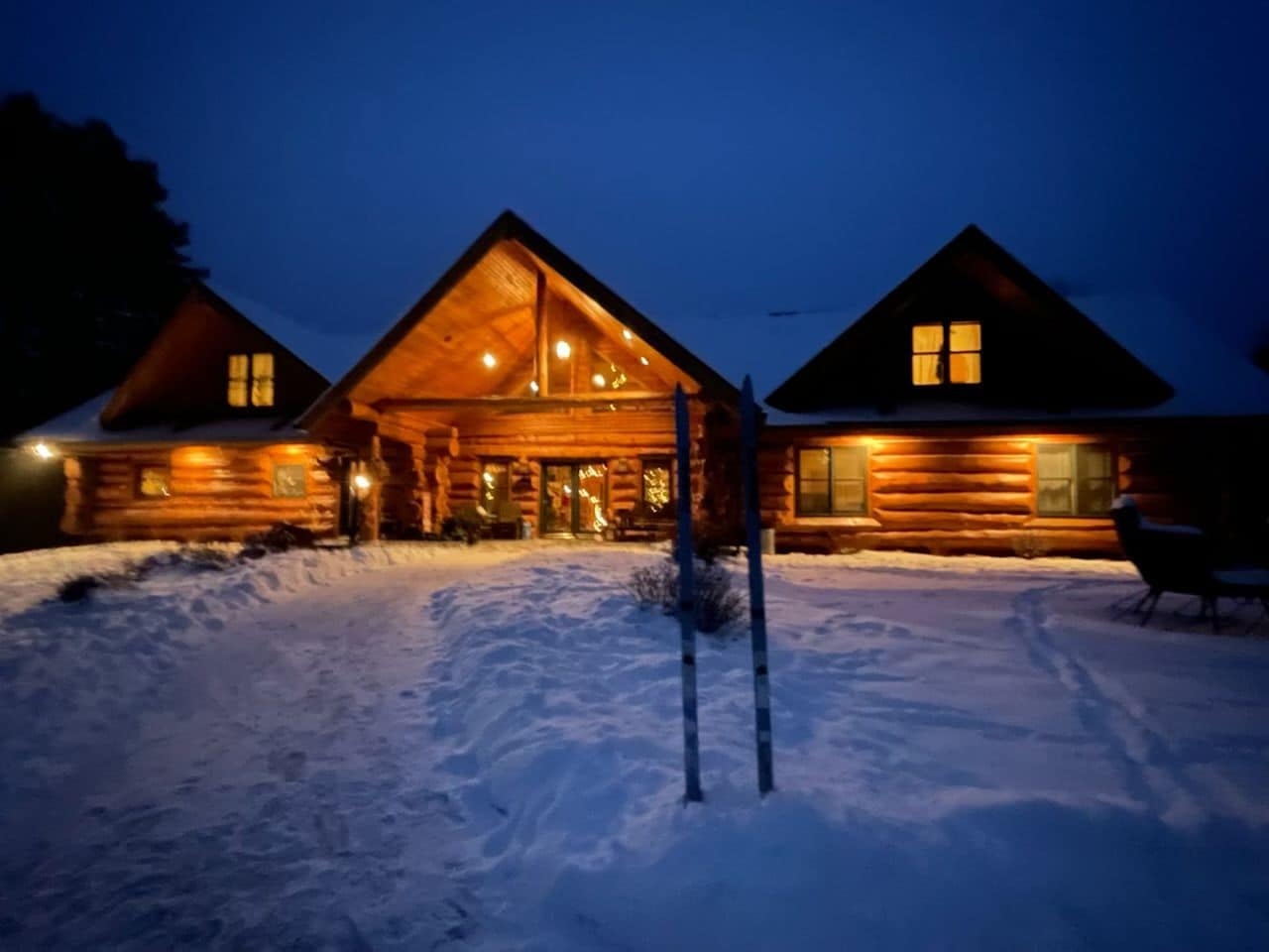 A log cabin with a large front porch and a snow-covered ground.