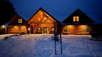 A log cabin with a large front porch and a snow-covered ground.
