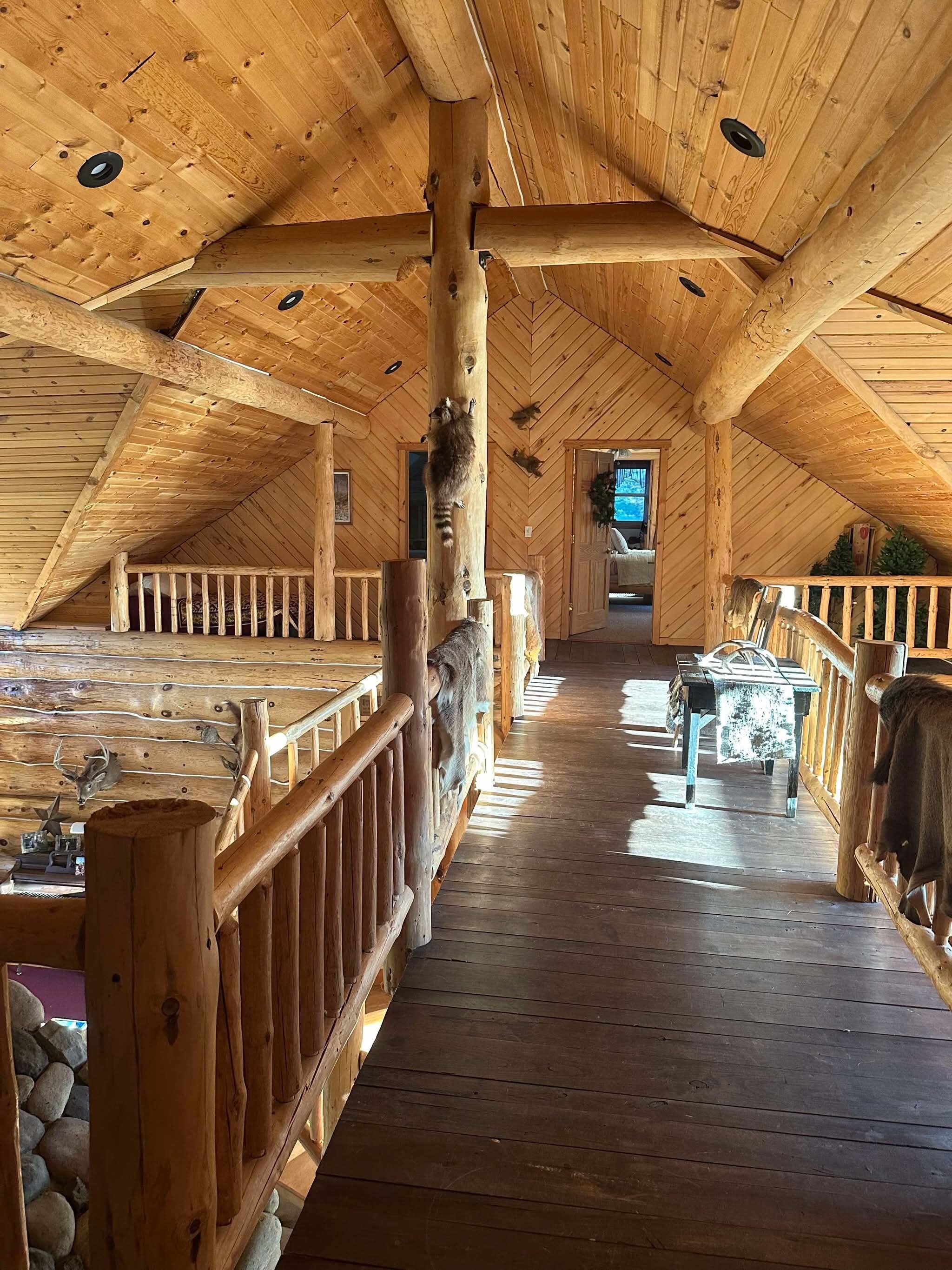 A wooden interior with a high ceiling, wooden railings, and a central walkway.