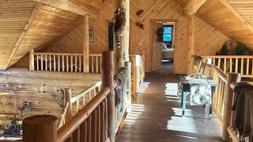 A wooden interior with a high ceiling, wooden railings, and a central walkway.
