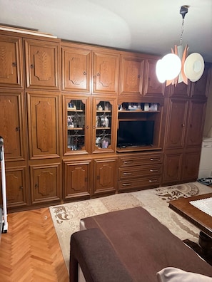 Quarto com armários de madeira, televisão e tapete estampado.