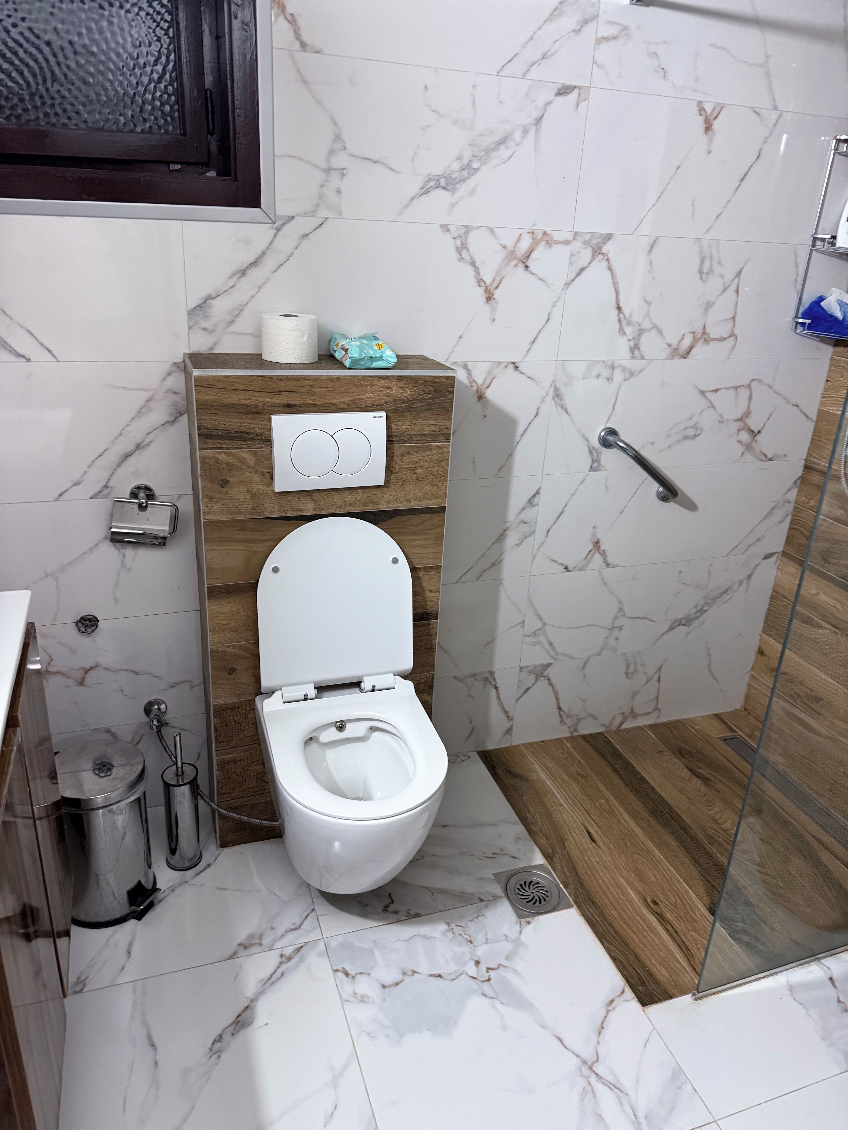 Casa de banho moderna com sanita, bidé, secador de mãos e cabine de duche em vidro.