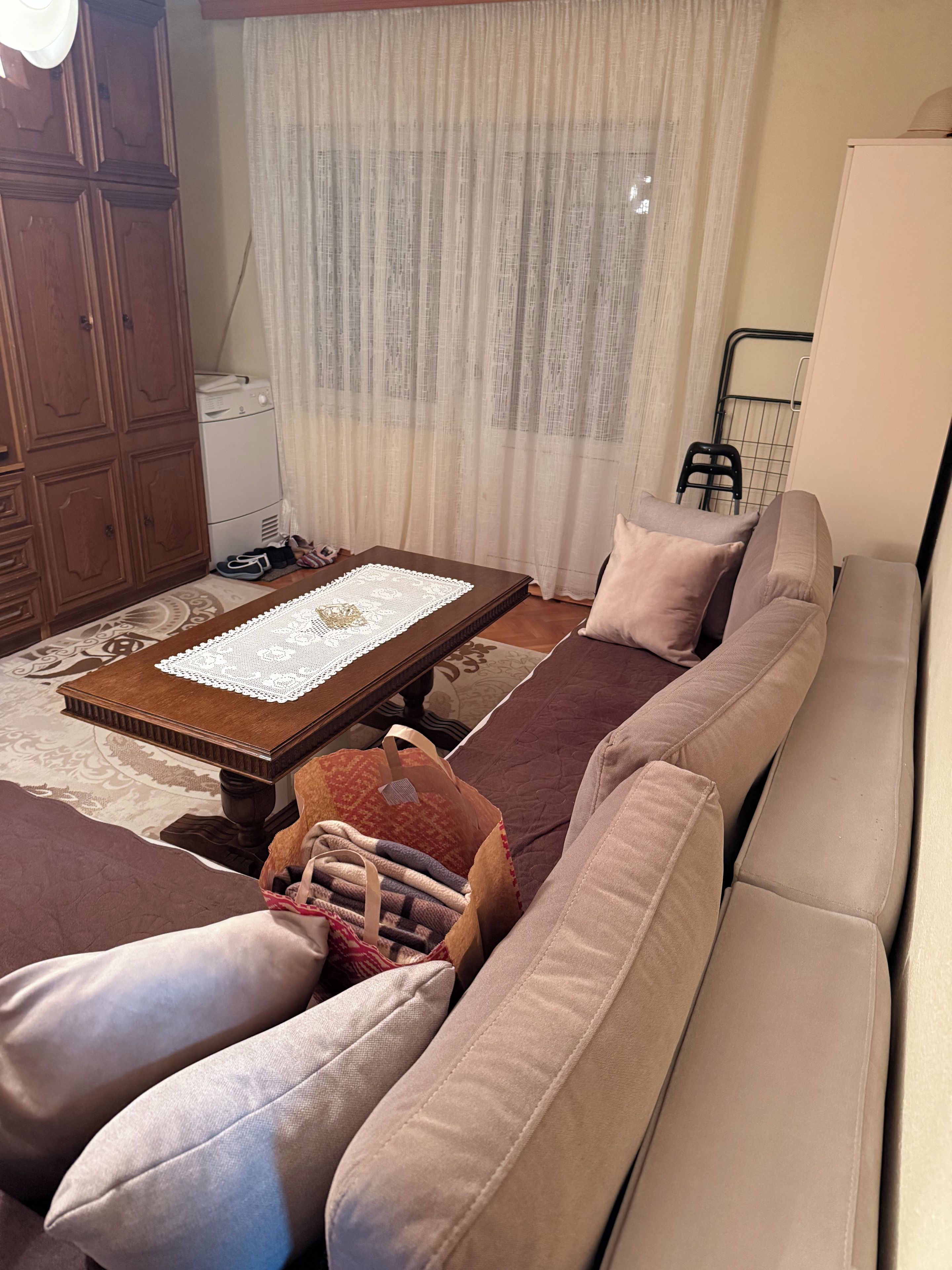 A living room with a sofa, a coffee table, a cabinet, and a radiator.