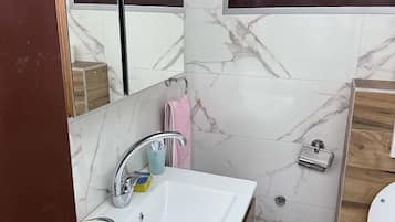 A bathroom with a white sink, a mirror, a window, and a toilet.